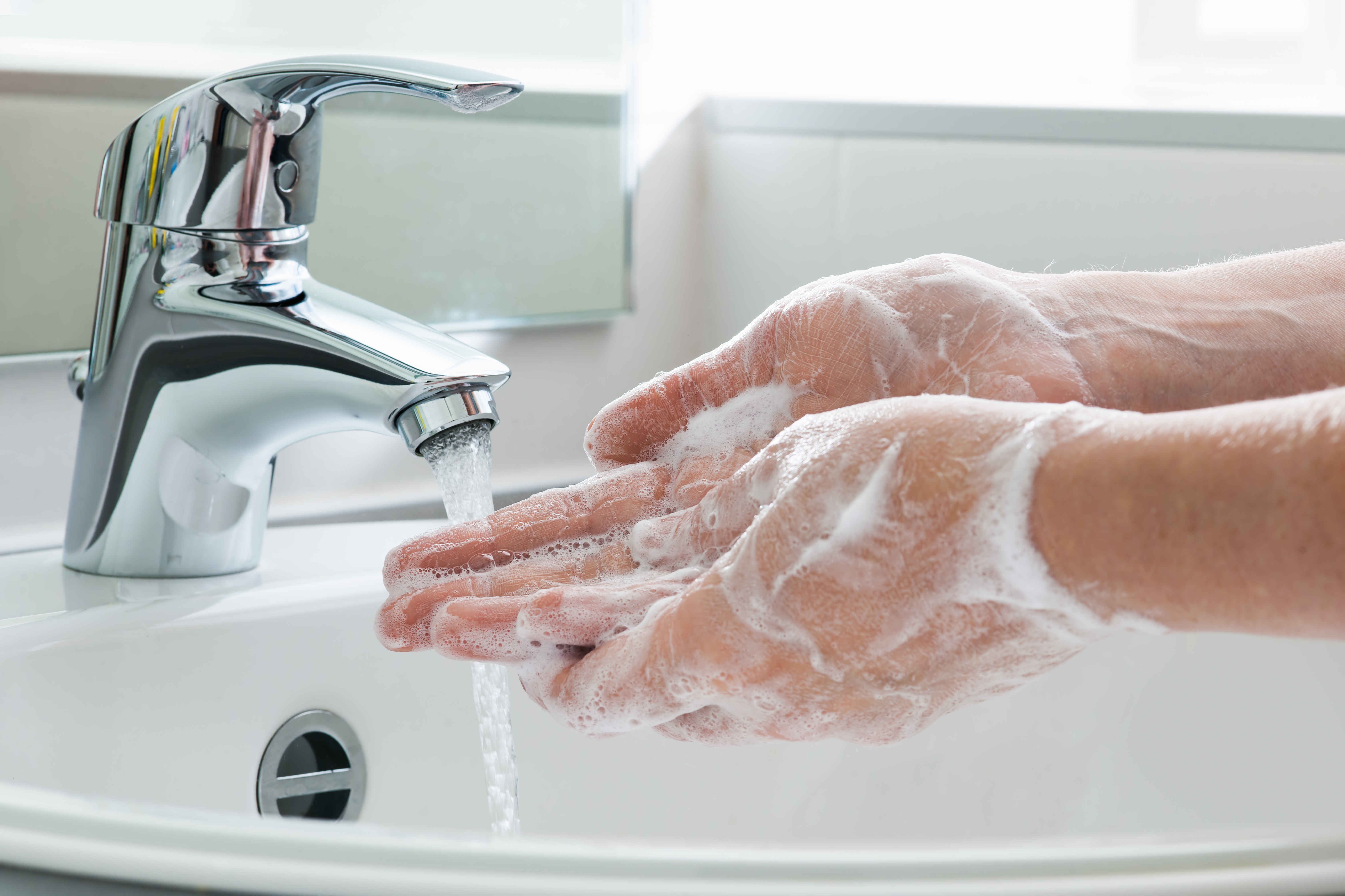 Person washing their hands with soap under running water.